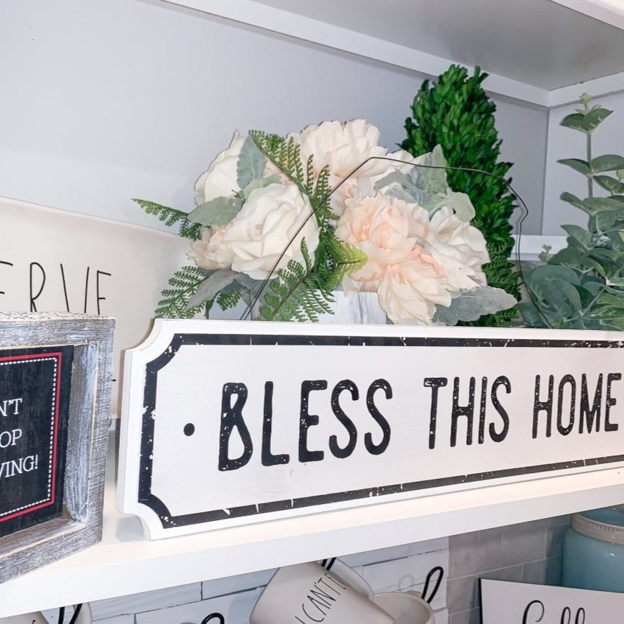 Farmhouse Chic hanging wood sign with 'Bless This Home' and 'Eat Good Food' messages, featuring a rustic white and black design.