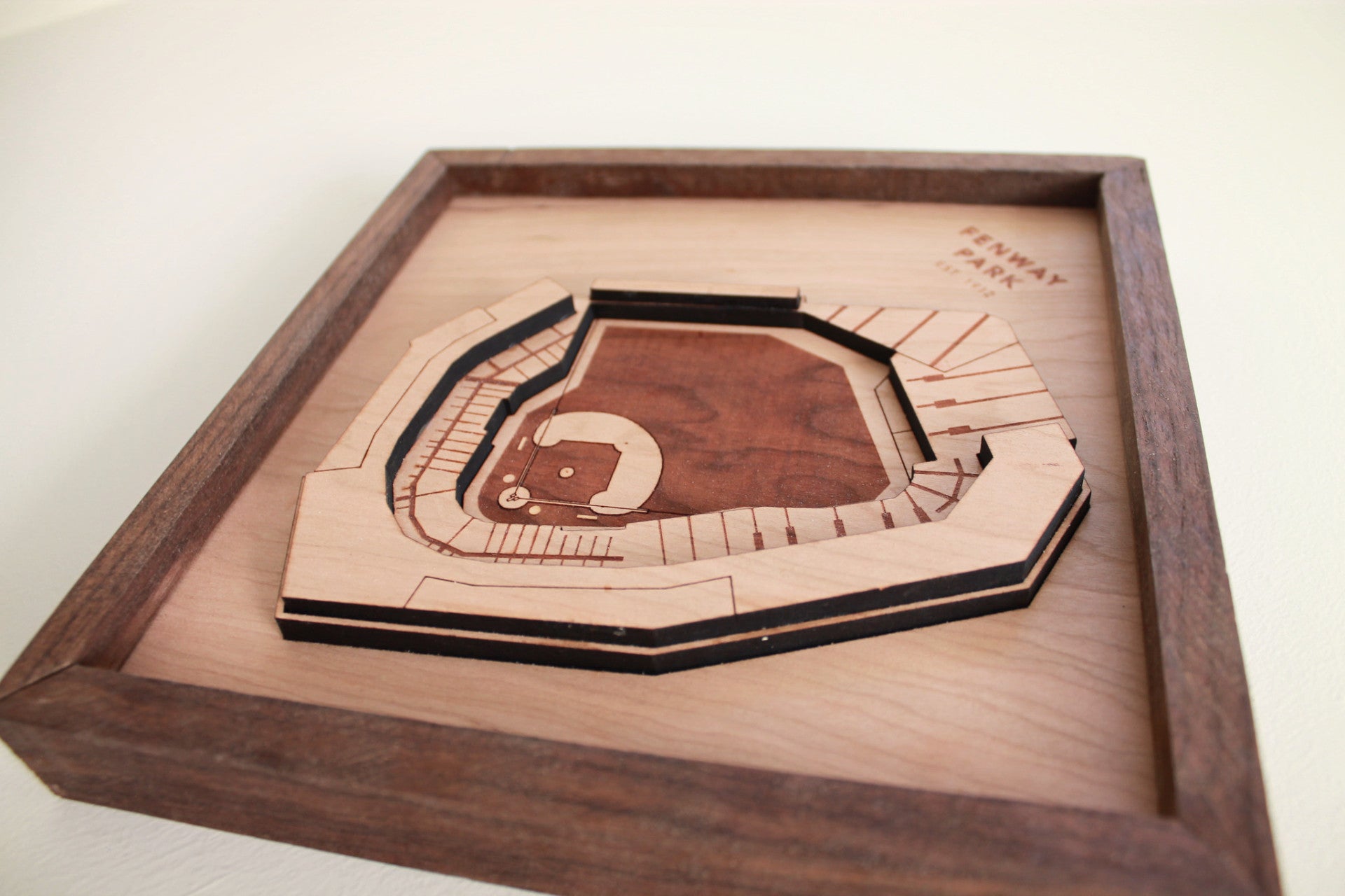 A beautifully crafted replica of Fenway Park, showcasing iconic features like the Green Monster and foul poles, framed in black walnut.