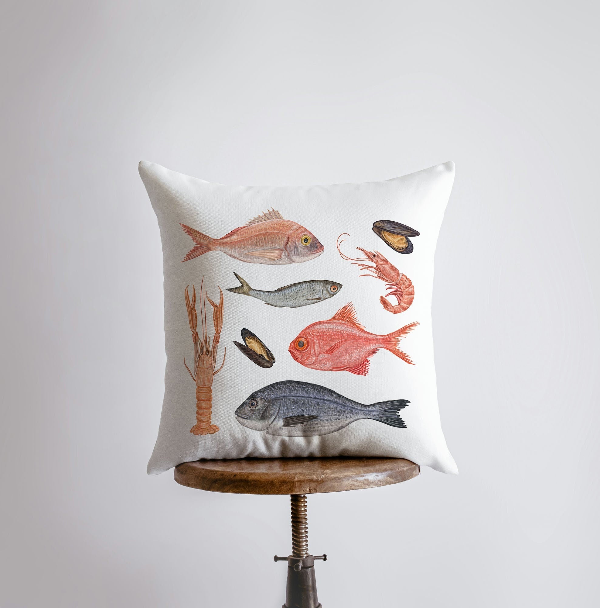 A stylish throw pillow featuring a fish and crustacean pattern, perfect for coastal home decor.