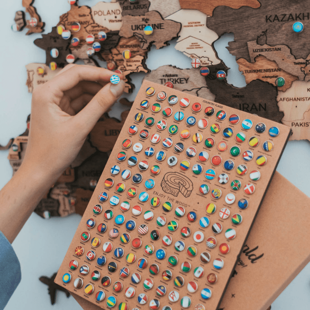 A collection of colorful flag push pins representing various countries and states, perfect for marking travel destinations on a map.