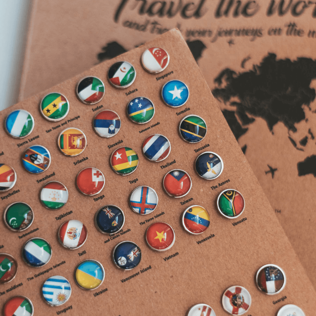 A collection of colorful flag push pins representing various countries and states, perfect for marking travel destinations on a map.