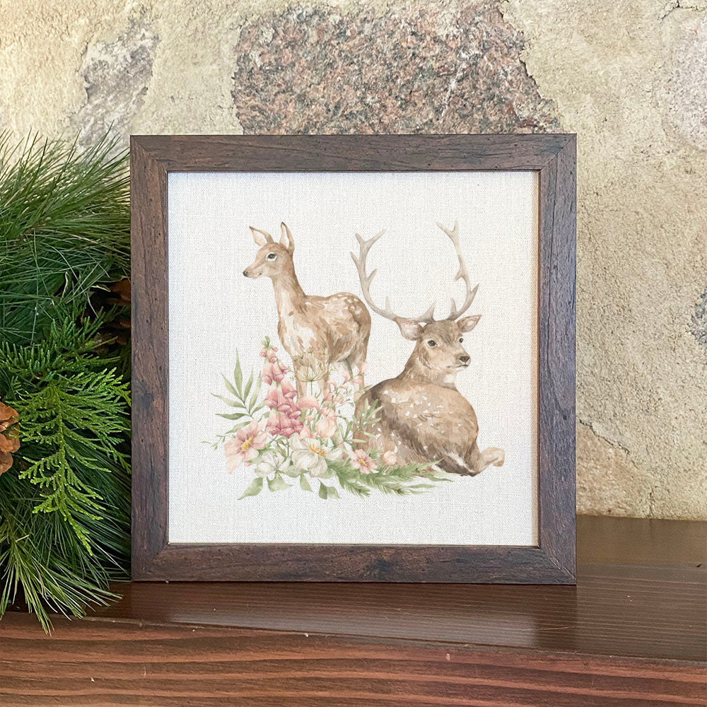 A beautifully framed sign featuring a floral deer design, set against a neutral linen-look background, perfect for home decor.