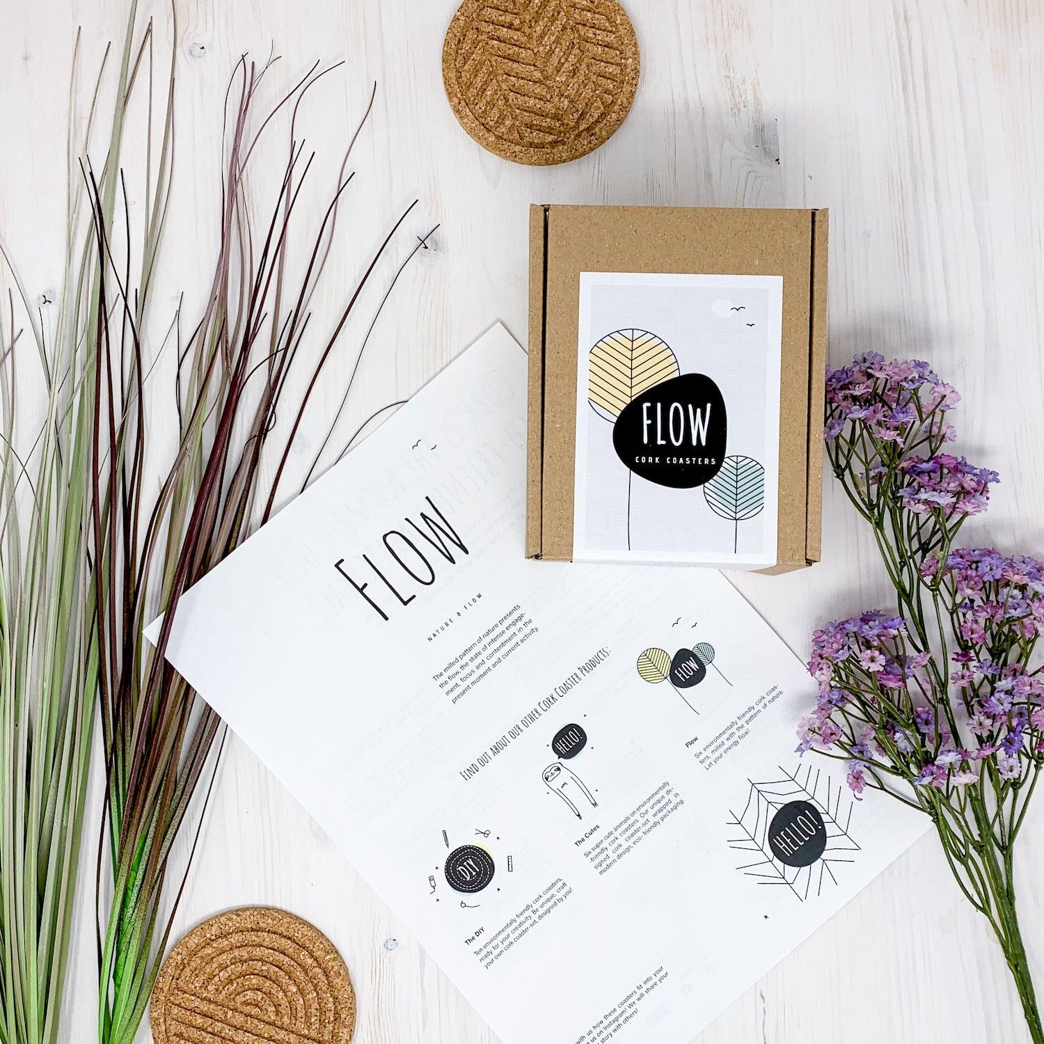 A set of six round cork coasters with nature-inspired designs including waves, leaves, and mountains, elegantly displayed on a wooden table.