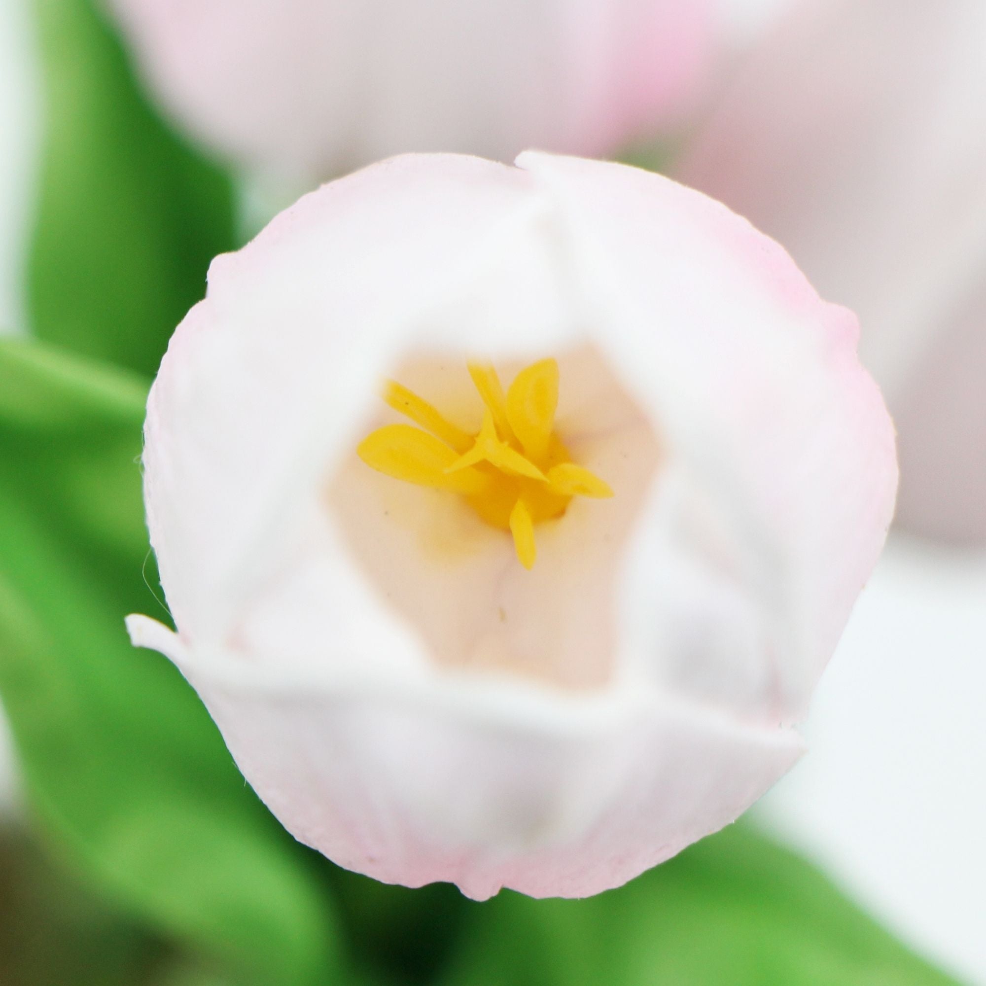 A vibrant arrangement of pink artificial tulips in a modern ceramic bowl, showcasing lush green foliage.