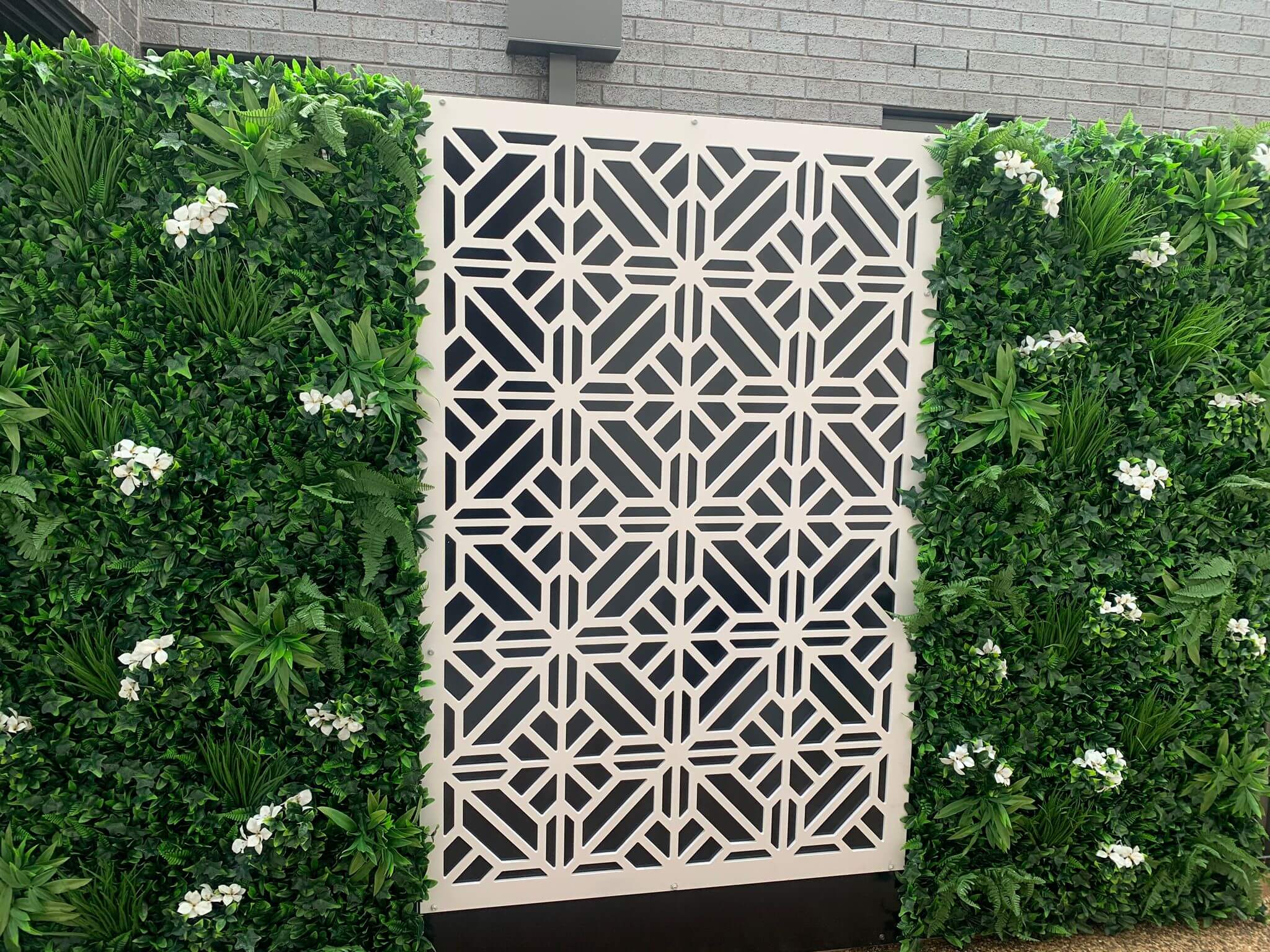 A vibrant Flowering White Jasmine Fake Green Wall showcasing lush greenery and white flowers, perfect for indoor and outdoor decor.