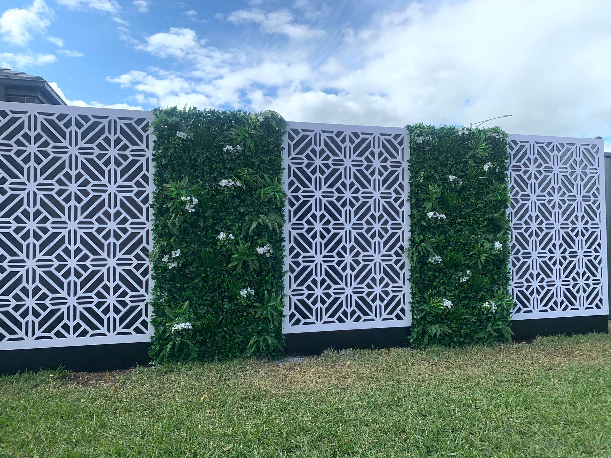 A vibrant Flowering White Jasmine Fake Green Wall showcasing lush greenery and white flowers, perfect for indoor and outdoor decor.