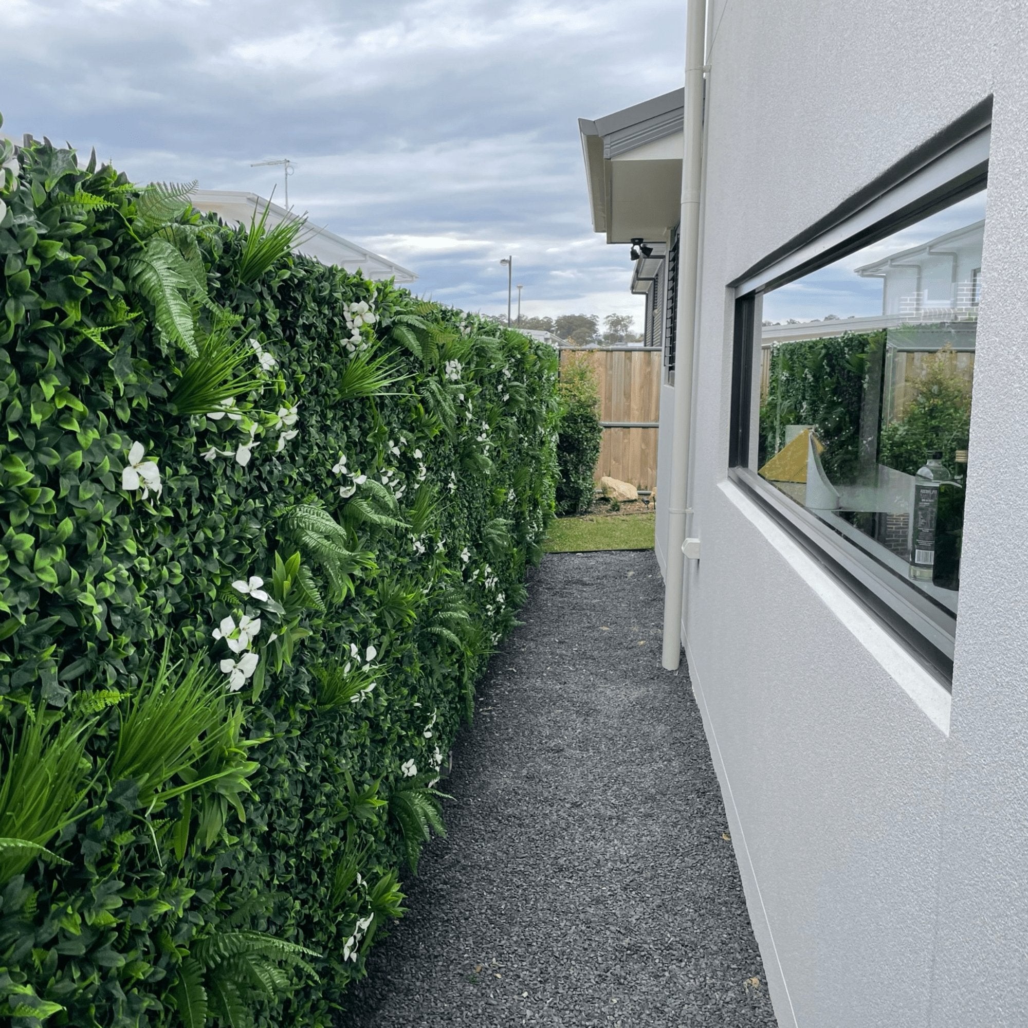 A vibrant Flowering White Jasmine Fake Green Wall showcasing lush greenery and white flowers, perfect for indoor and outdoor decor.