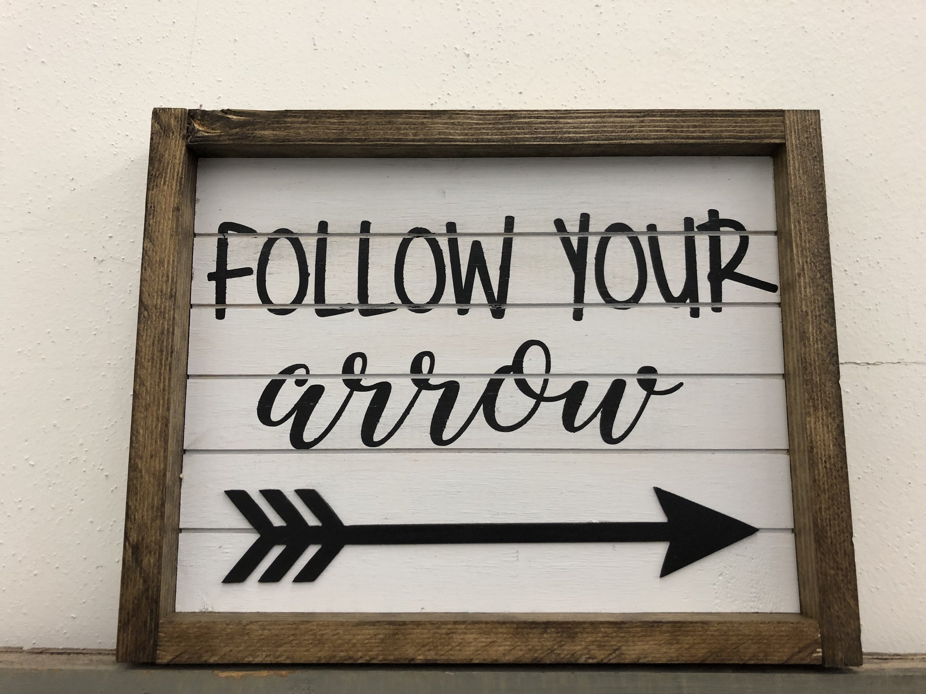 Follow Your Arrow wood wall art featuring a rustic frame and a steel arrow, perfect for home decor and motivation.