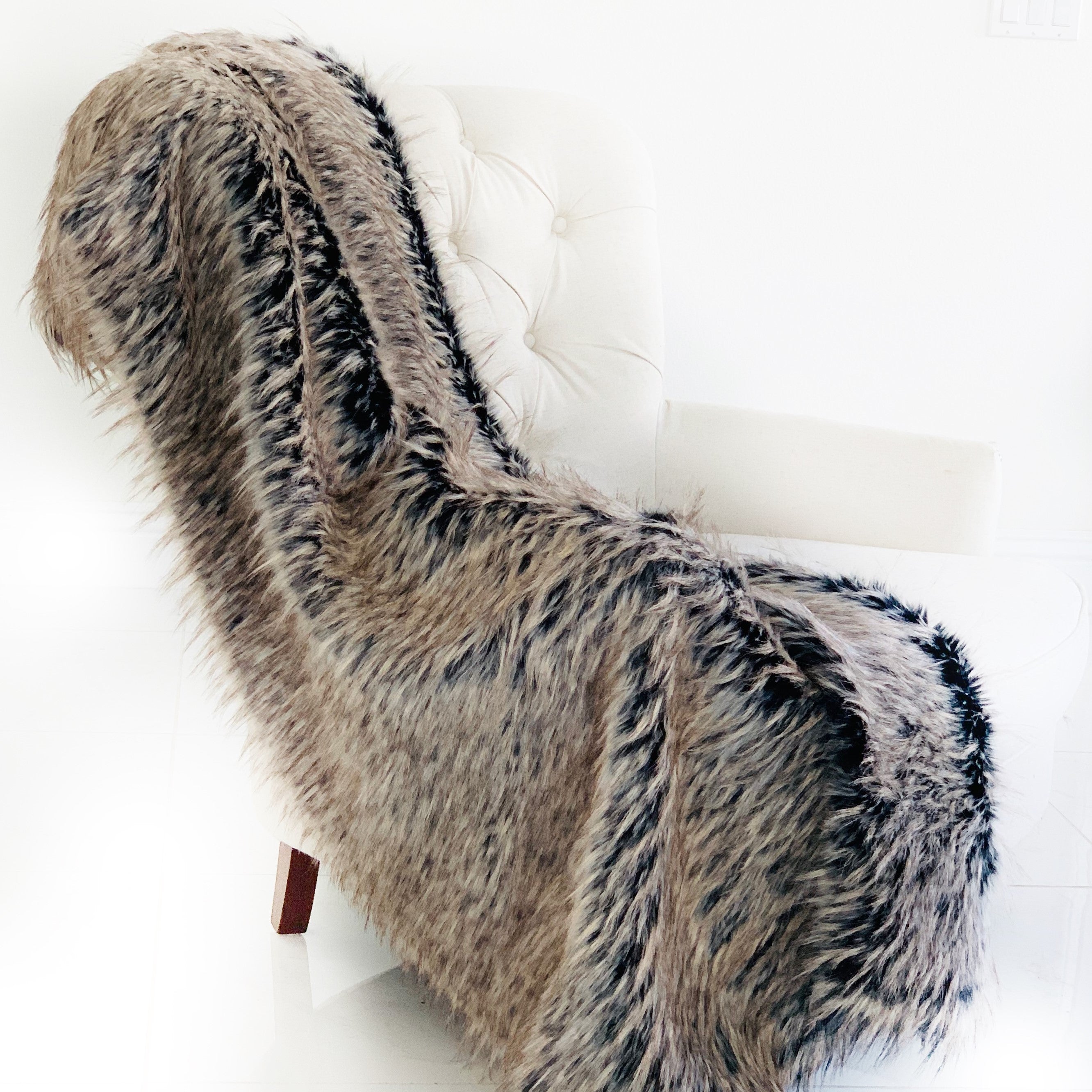 Foxy Brown Gray Plush Handmade Luxury Faux Fur Throw blanket draped elegantly on a couch, showcasing its soft texture and reversible design.