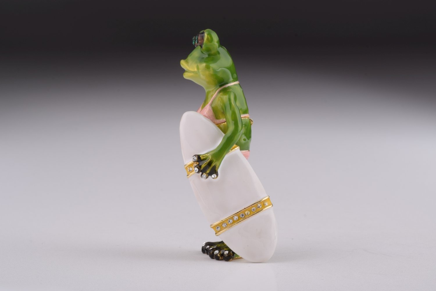 A beautifully crafted Frog Holding a Surfboard trinket box, adorned with Austrian crystals and plated with 24K gold, showcasing intricate details.