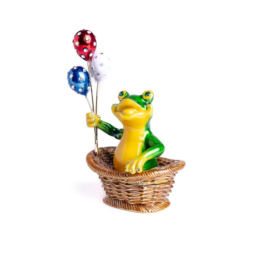 A handmade trinket box featuring a frog sitting in a basket, holding colorful balloons, adorned with Austrian crystals and plated with 925 silver.