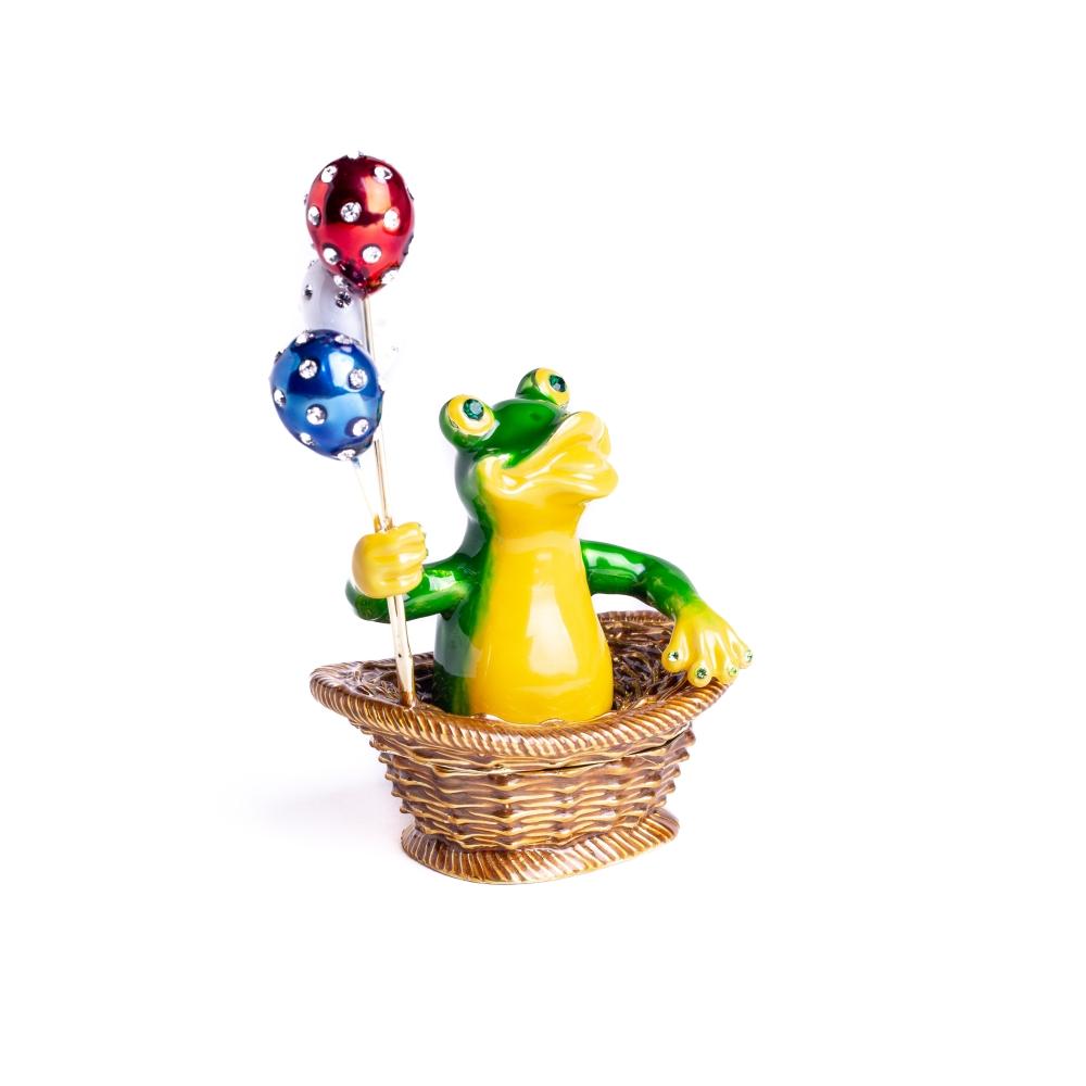 A handmade trinket box featuring a frog sitting in a basket, holding colorful balloons, adorned with Austrian crystals and plated with 925 silver.