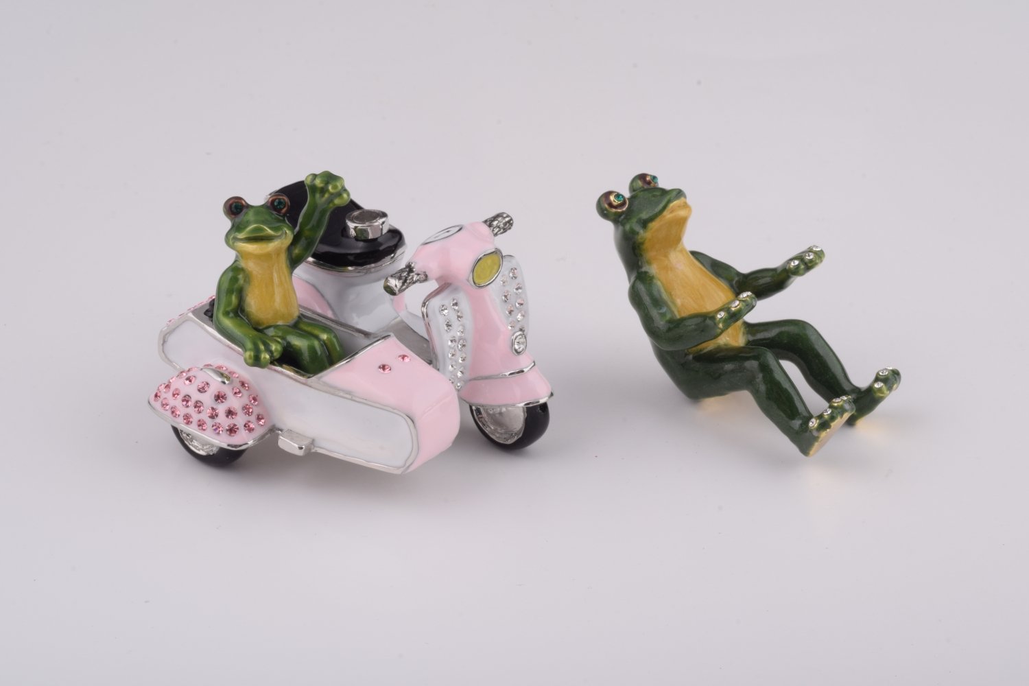 A whimsical trinket box featuring frogs riding a Vespa with a sidecar, adorned with Austrian crystals and gold plating.