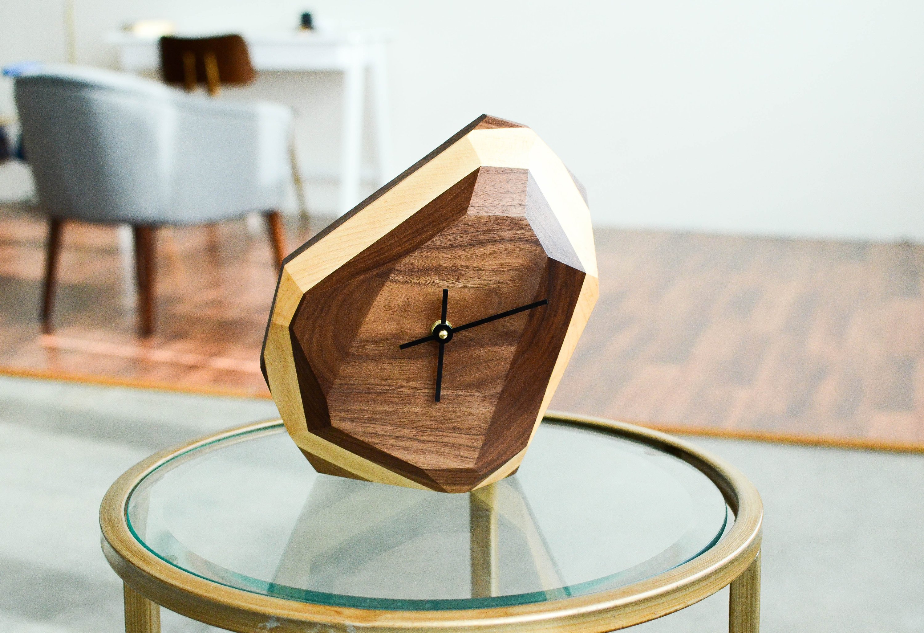 A modern geometric wall and table clock made from American hardwood, showcasing unique wood grain patterns and a quartz crystal-inspired design.