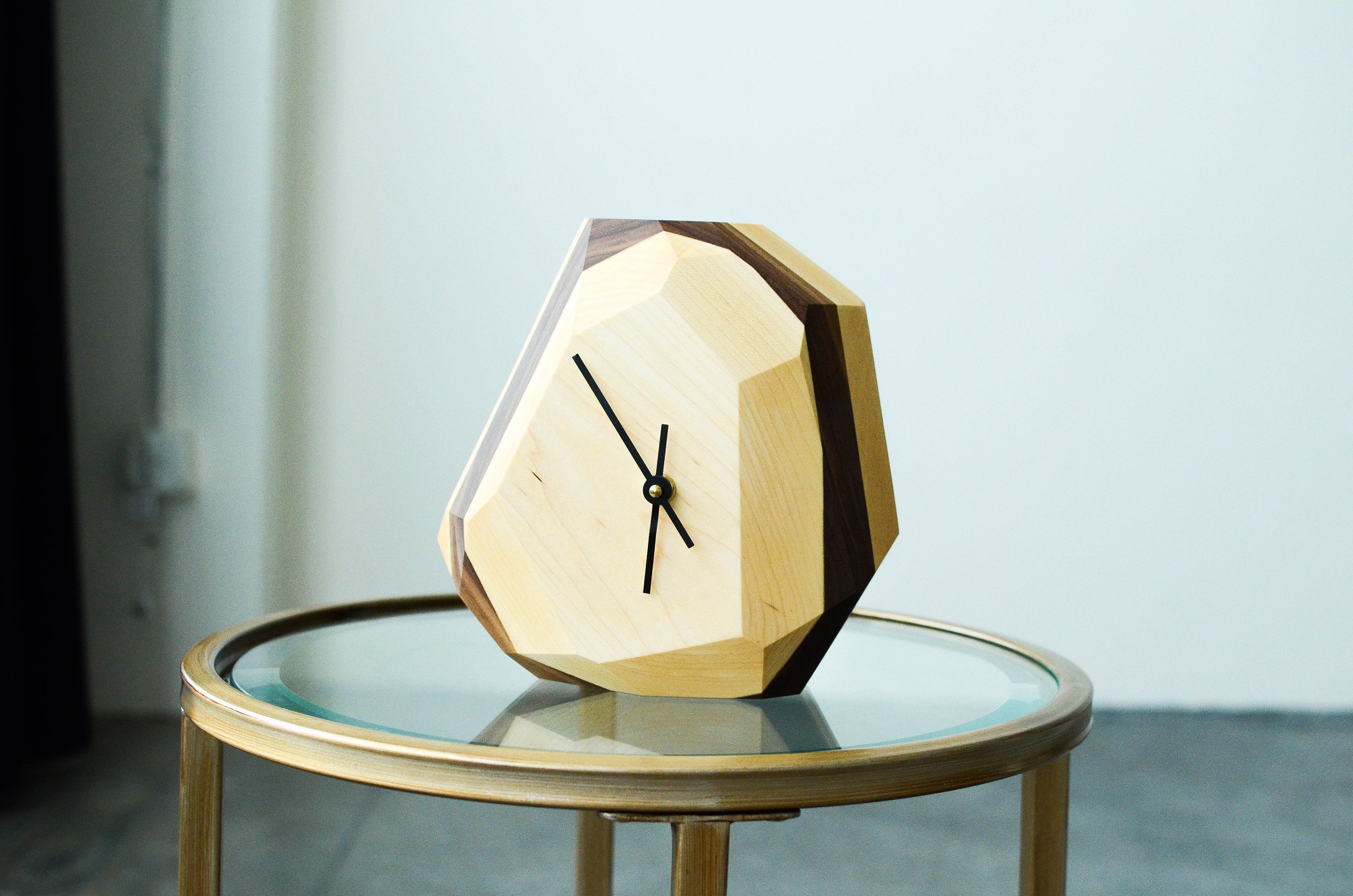 A modern geometric wall and table clock made from American hardwood, showcasing unique wood grain patterns and a quartz crystal-inspired design.