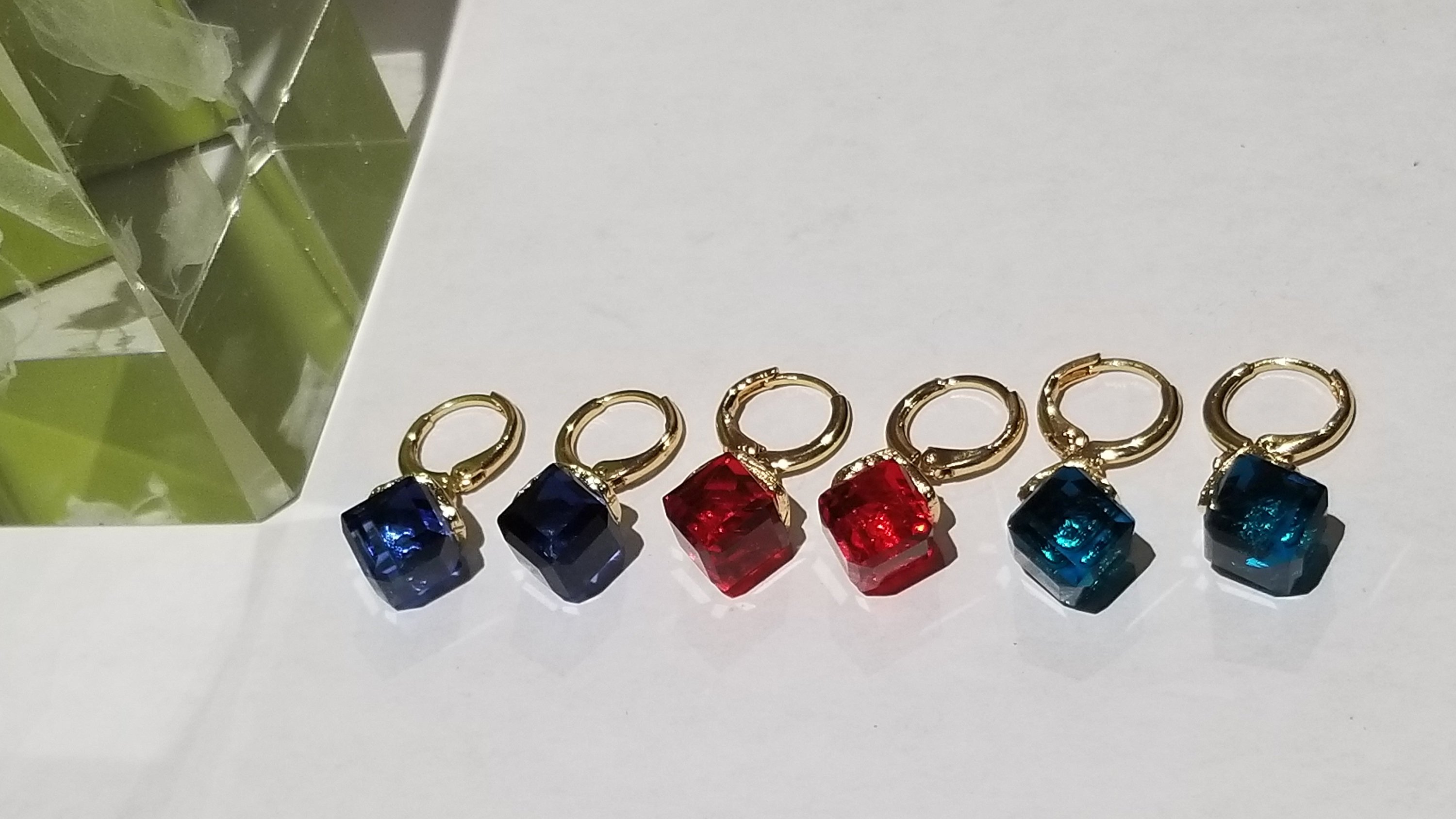 Stylish glass cube crystal earrings in blue, red, and peacock blue colors, showcasing their translucent design.