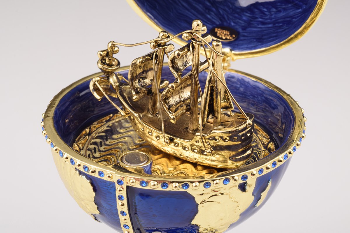 A beautifully crafted Globe Faberge Egg trinket box featuring a sailing ship design, adorned with Austrian crystals and plated in 24K gold or 925 silver.