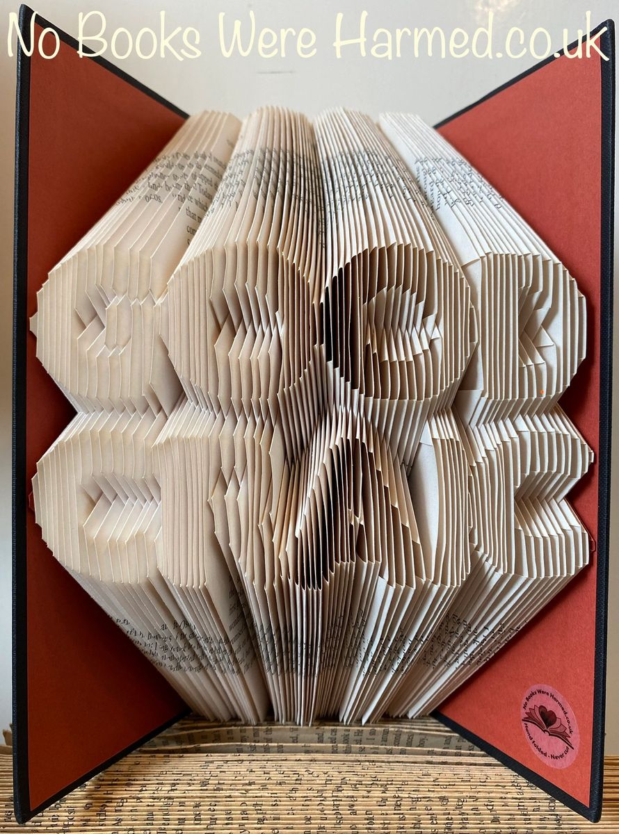 A beautifully crafted piece of book art made from vintage books, showcasing intricate hand-folded pages in various colors and textures.