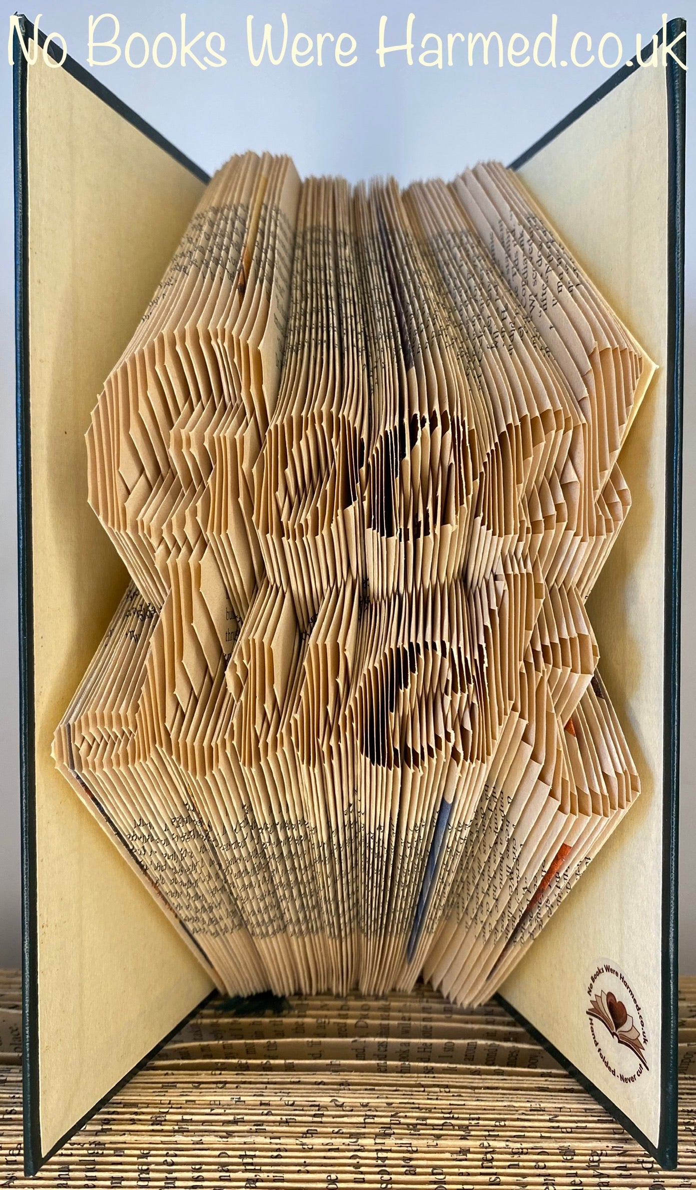 Hand-folded book art titled 'Good Luck', showcasing intricate designs from vintage books with unique colors and textures.