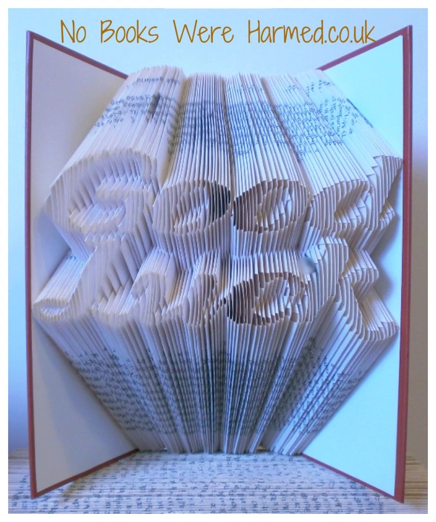 Hand-folded book art titled 'Good Luck', showcasing intricate designs from vintage books with unique colors and textures.