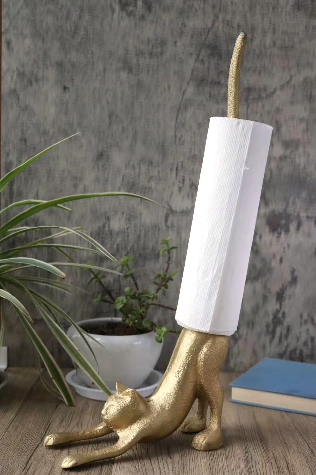 A whimsical gold cat paper towel holder made of cast iron, featuring a stretching cat design with a tail that holds paper towel rolls.