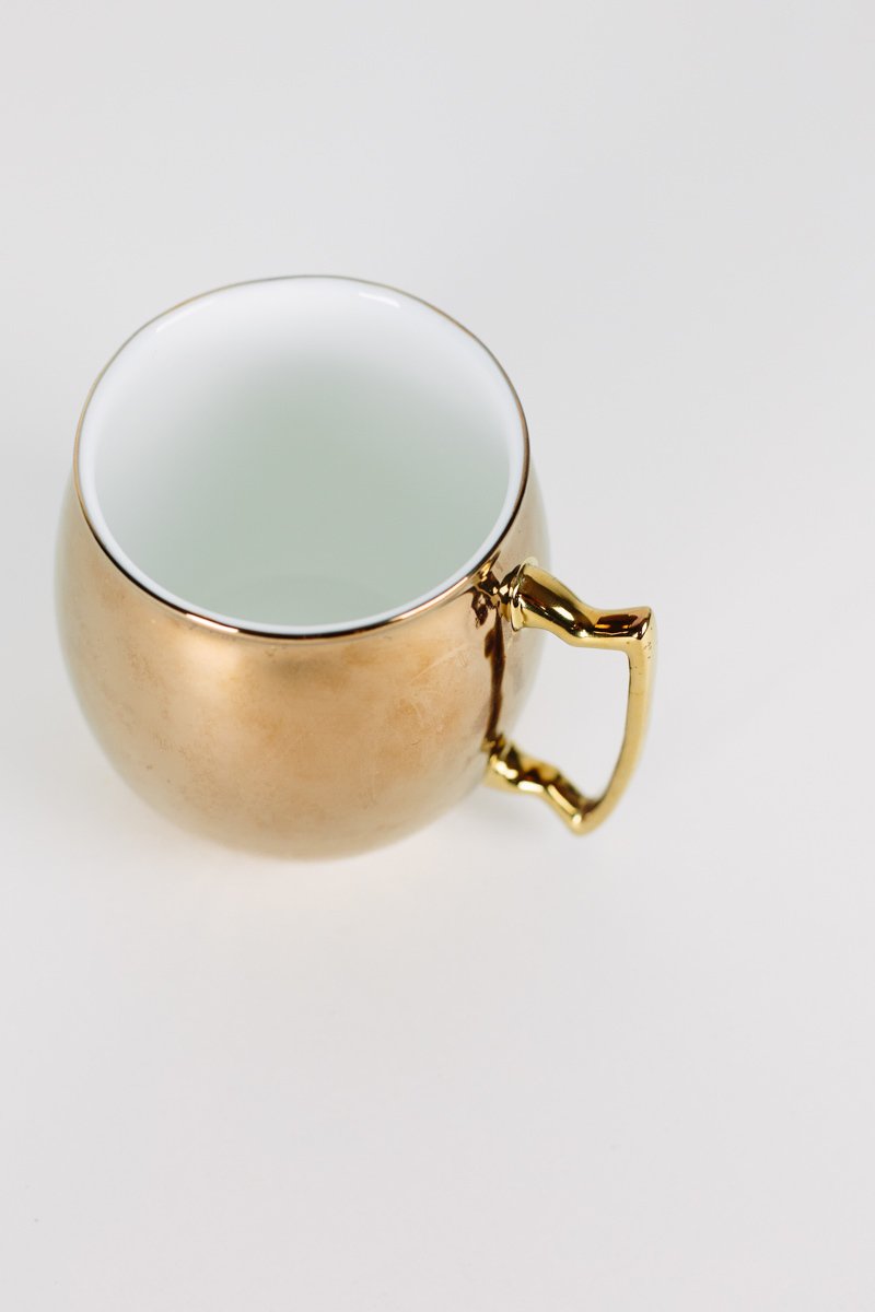 Gold Moscow Fuel Mug shaped like a cocktail with a copper/gold exterior and white interior, perfect for coffee or cocktails.