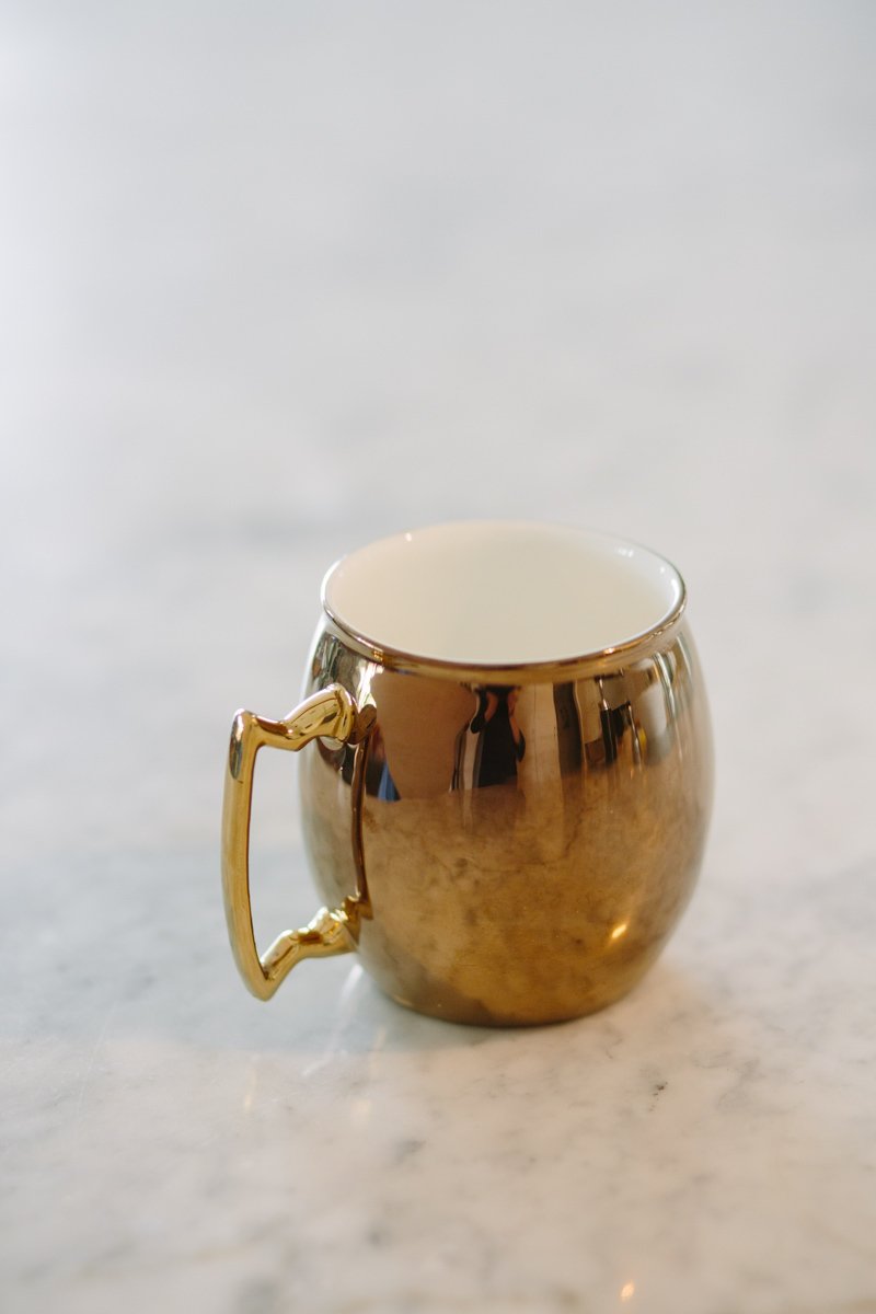 Gold Moscow Fuel Mug shaped like a cocktail with a copper/gold exterior and white interior, perfect for coffee or cocktails.