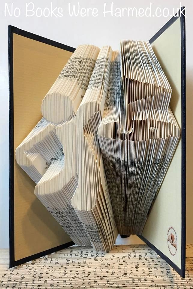 Hand-folded book art depicting a golfer achieving a hole in one, crafted from vintage books with intricate folds and unique colors.