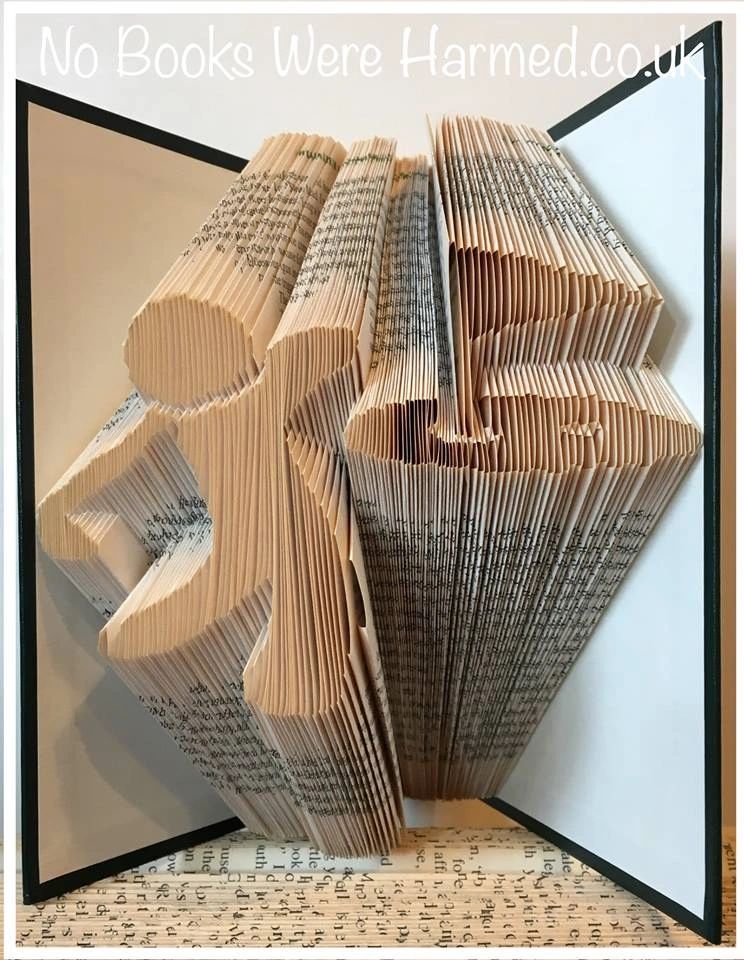 Hand-folded book art depicting a golfer achieving a hole in one, crafted from vintage books with intricate folds and unique colors.