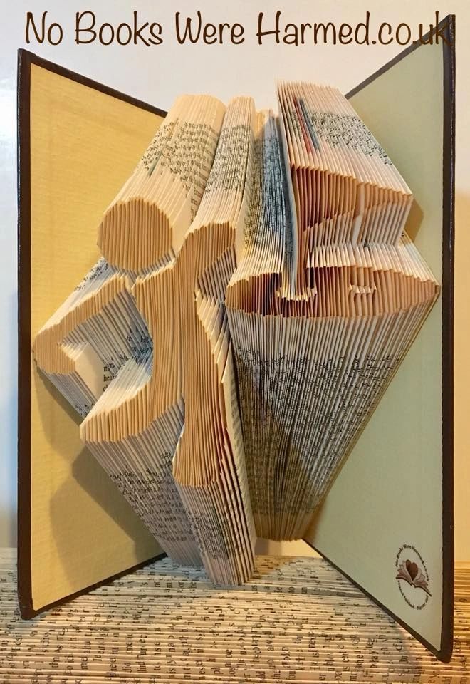 Hand-folded book art depicting a golfer achieving a hole in one, crafted from vintage books with intricate folds and unique colors.