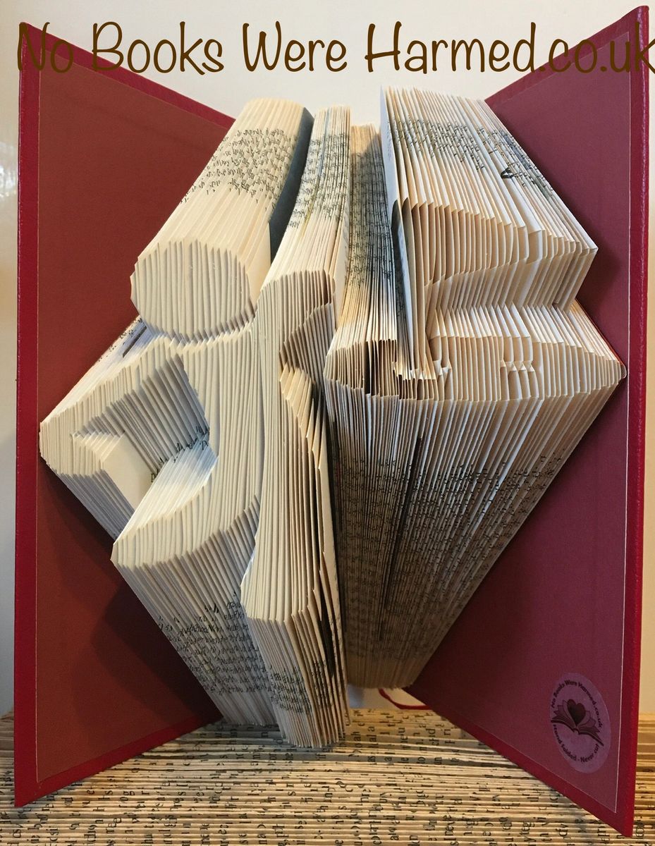 Hand-folded book art depicting a golfer achieving a hole in one, crafted from vintage books with intricate folds and unique colors.