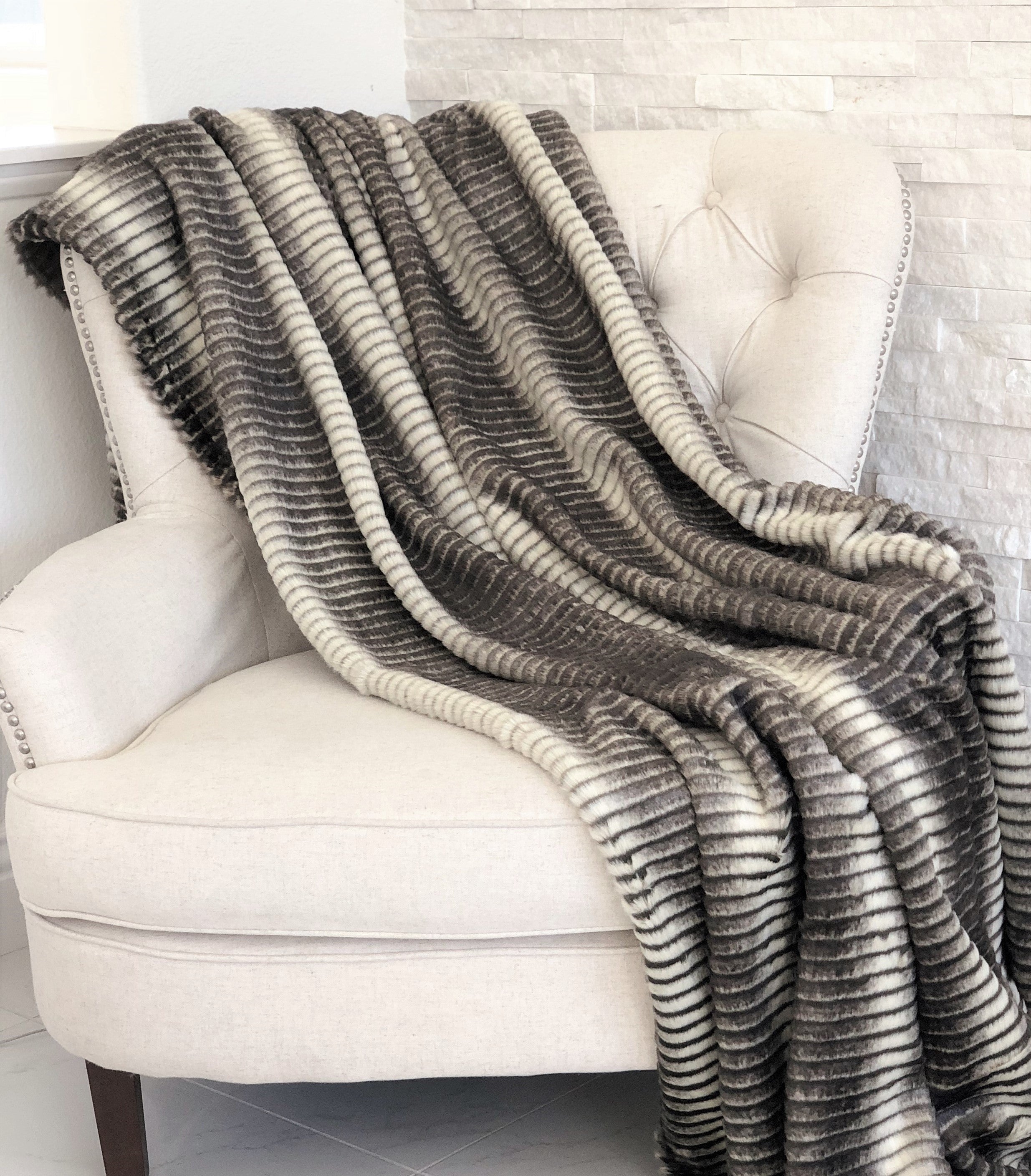 Gray and taupe faux fur luxury throw blanket with plush texture, perfect for cozying up any space.