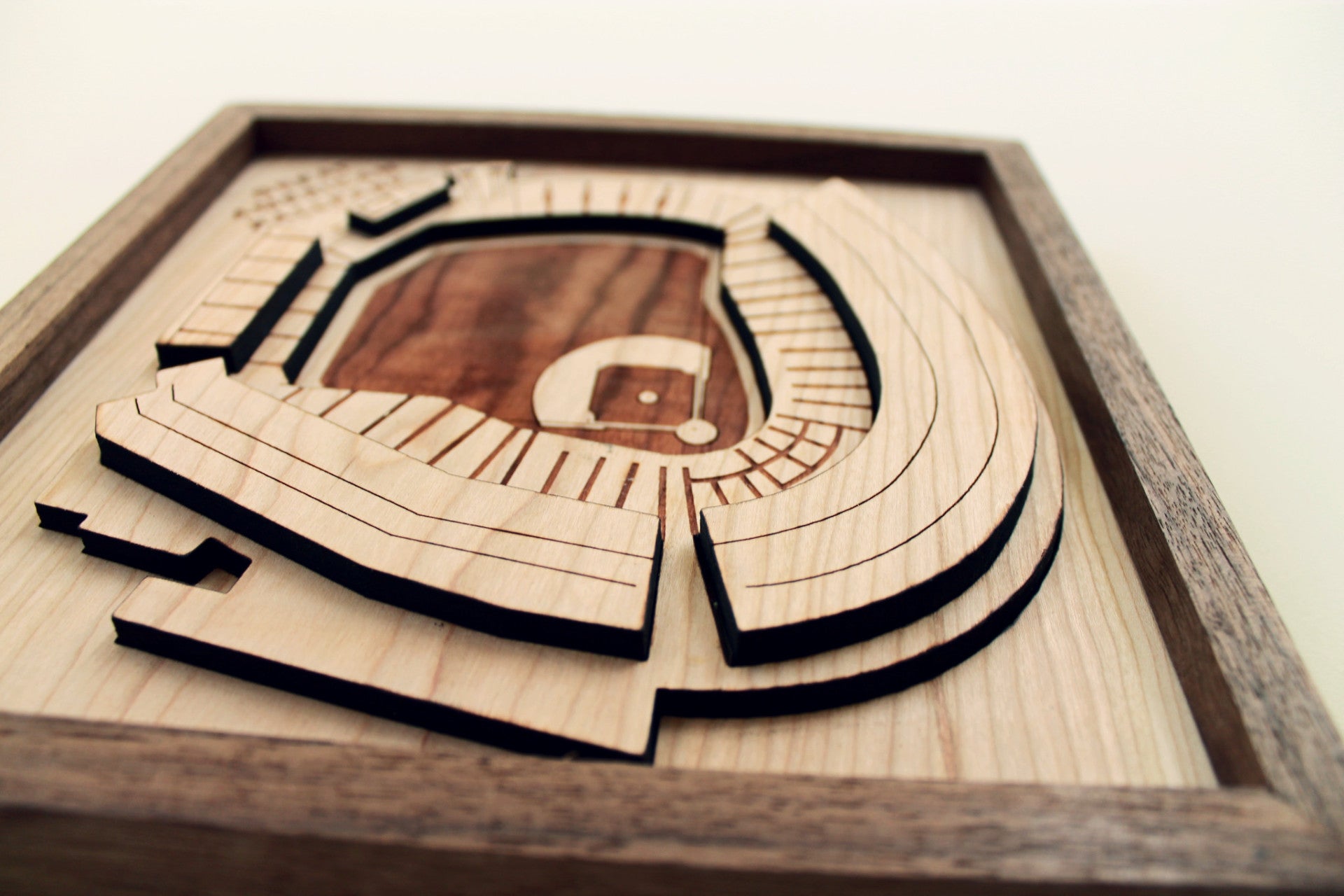 A beautifully crafted wooden model of the Great American Ballpark, featuring intricate details like smokestacks and a riverboat, framed in black walnut.