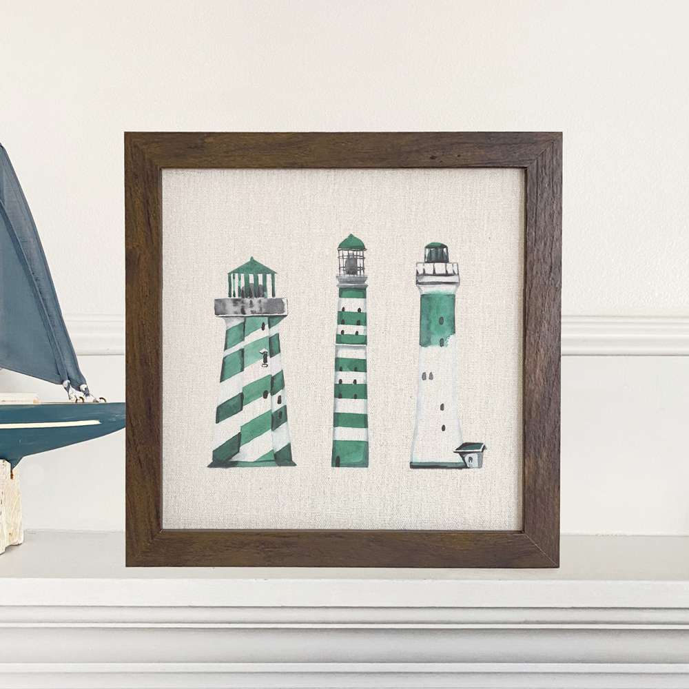 A beautifully framed sign featuring green lighthouses on a linen-look background, perfect for home decor.