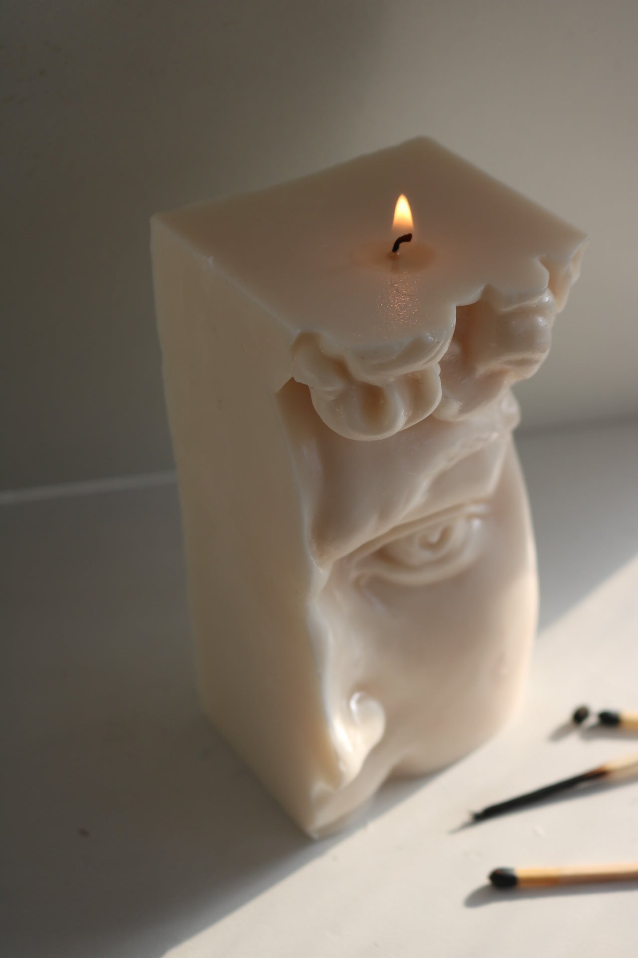 Half David sculptural candle in a soft neutral color, showcasing its unique artistic design and elegant form, perfect for home decor.