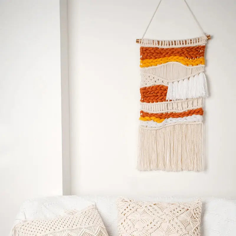 Hand Woven Cotton Wall Art in vibrant orange and white, featuring chunky elements on a wooden stick, showcasing intricate craftsmanship.