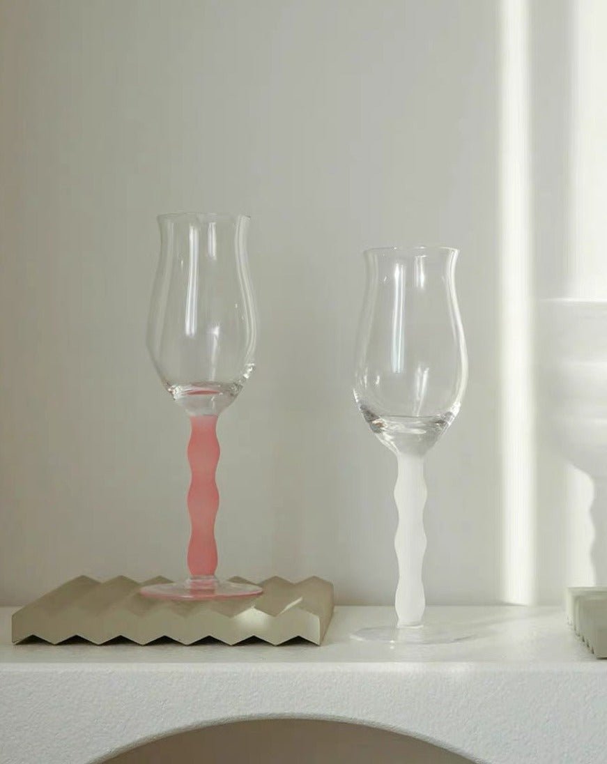 Set of 4 handblown retro rose wine glasses with colorful wavy stems, elegantly showcasing wine in transparent bowls.