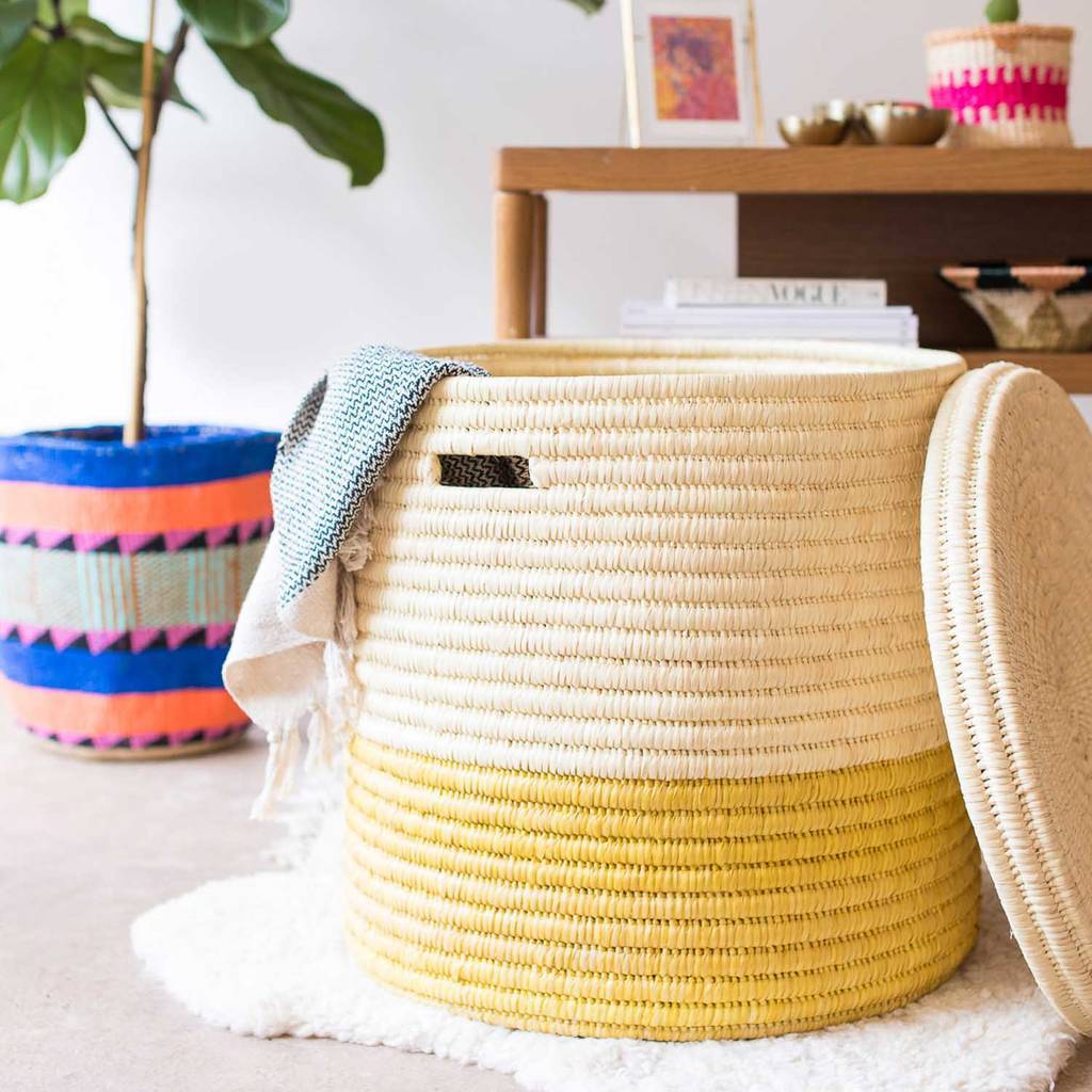 Handcrafted African laundry basket in vibrant sunflower yellow and burnt orange, showcasing intricate weaving from doum palm leaves.