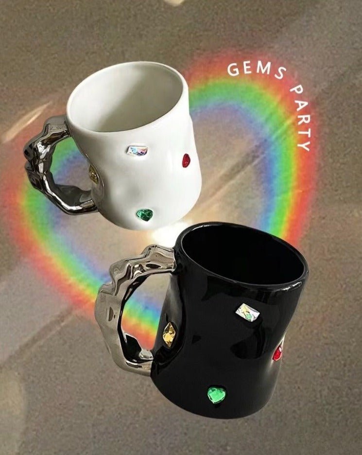 A pair of handmade ceramic coffee mugs featuring a gemstone design and wavy handles, perfect for couples.