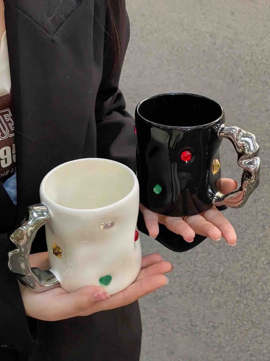 A pair of handmade ceramic coffee mugs featuring a gemstone design and wavy handles, perfect for couples.