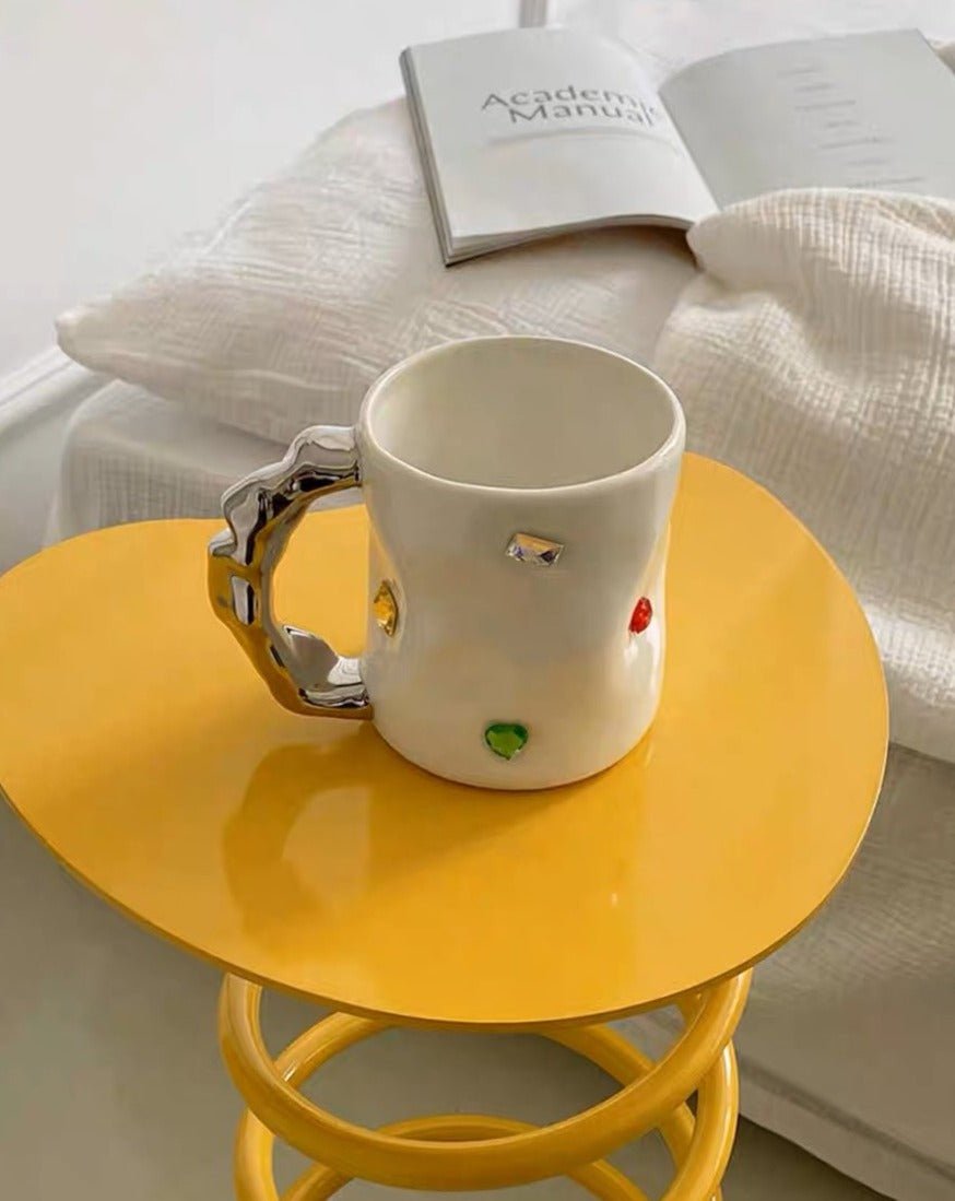 A pair of handmade ceramic coffee mugs featuring a gemstone design and wavy handles, perfect for couples.