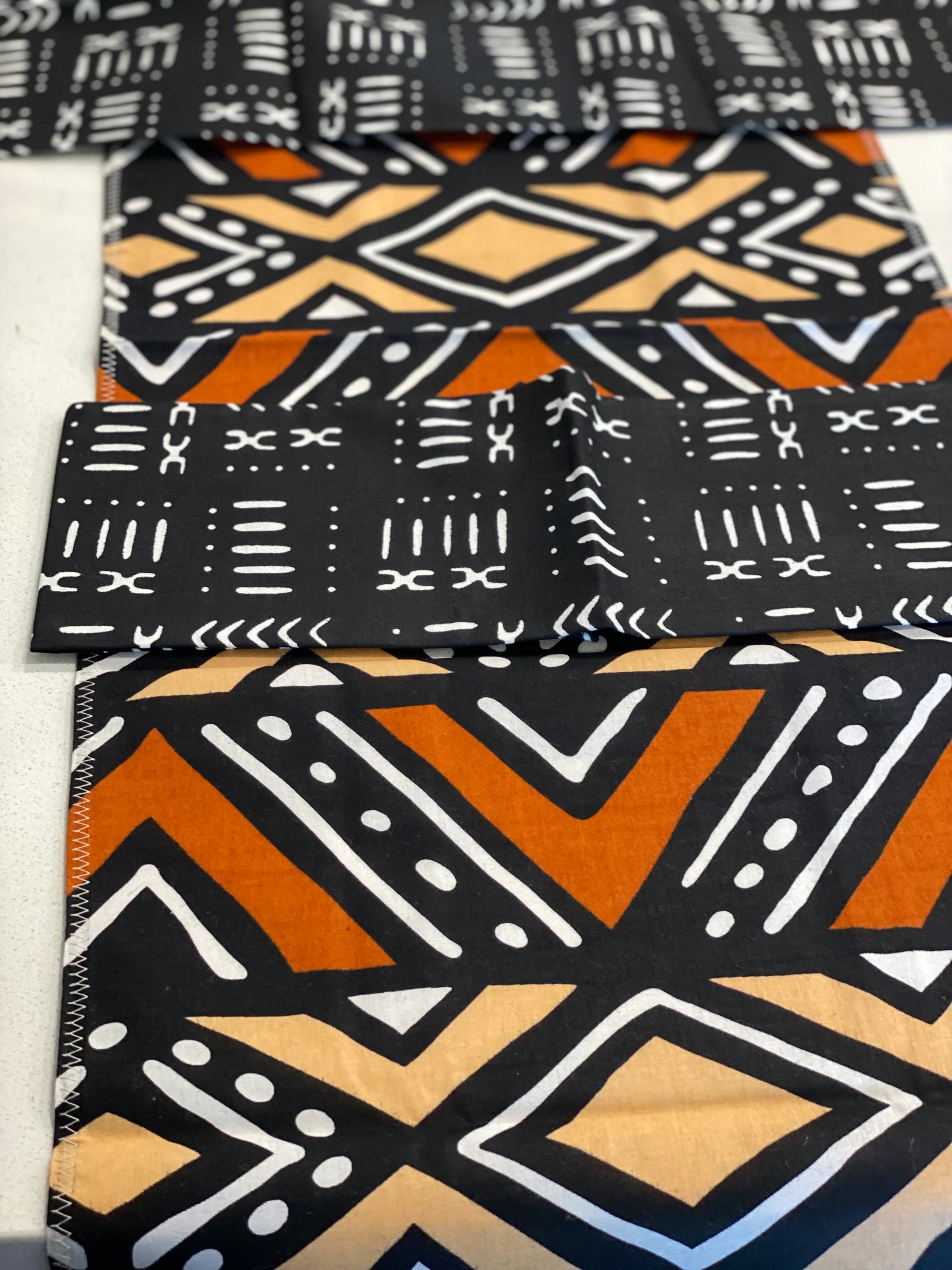 Handmade coffee table runner featuring vibrant orange Bologan wax print, showcasing intricate patterns and authentic Zimbabwean craftsmanship.