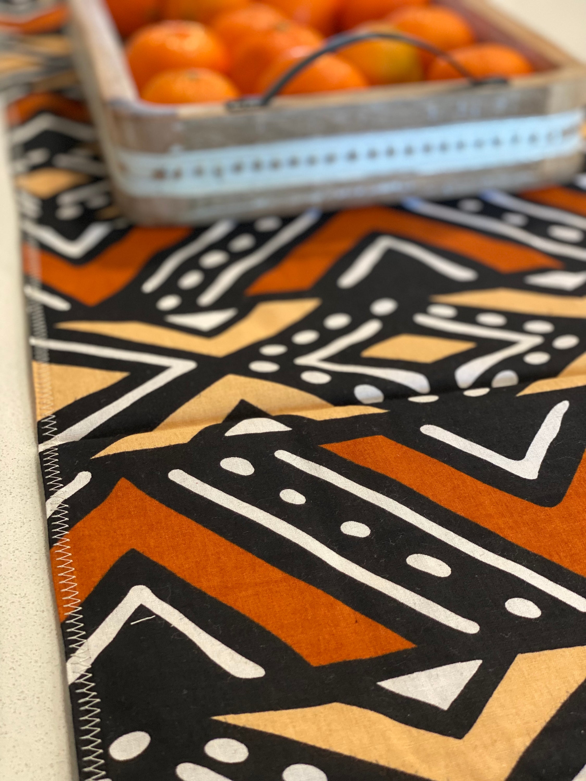 Handmade coffee table runner featuring vibrant orange Bologan wax print, showcasing intricate patterns and authentic Zimbabwean craftsmanship.