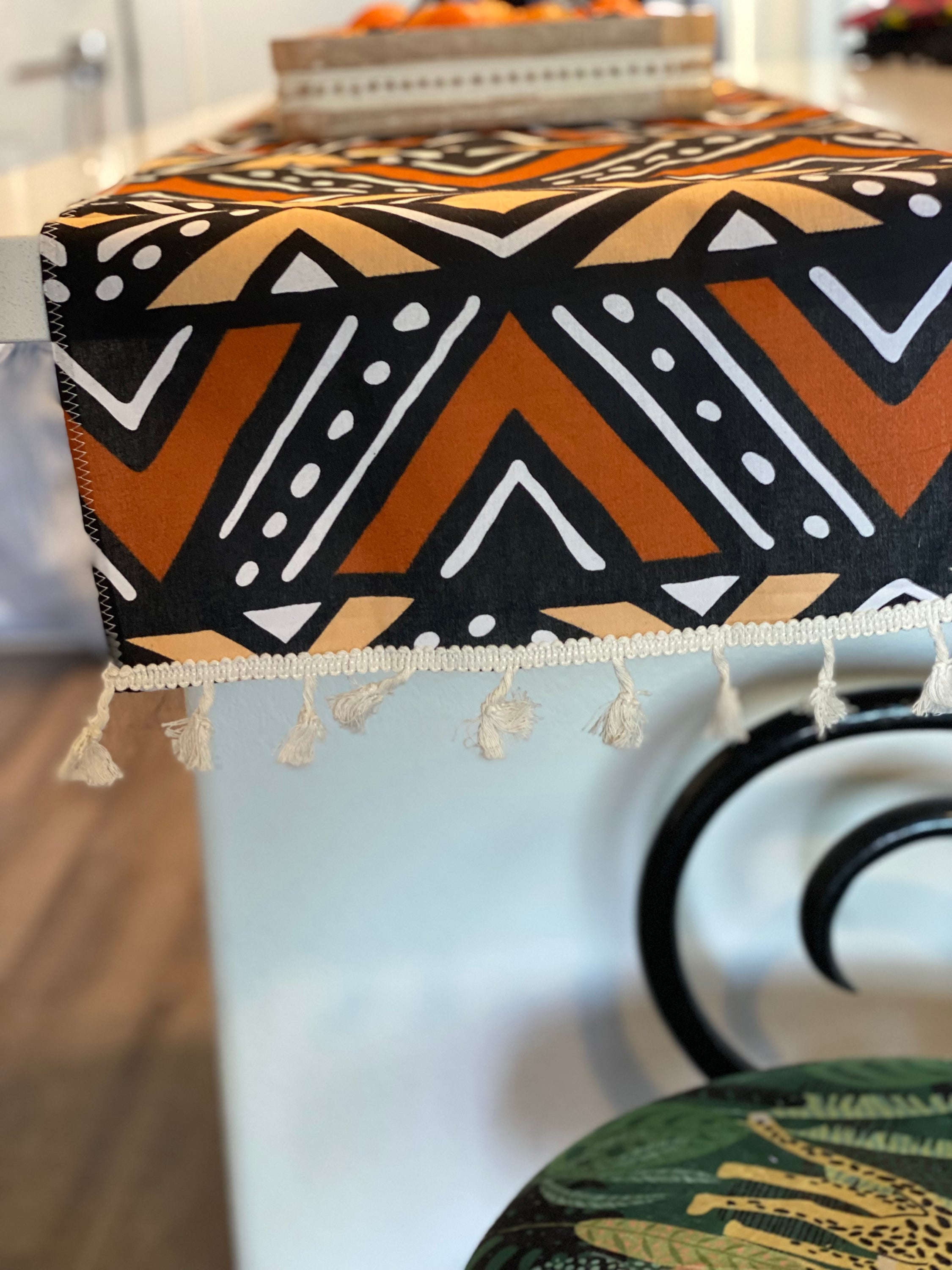 Handmade coffee table runner featuring vibrant orange Bologan wax print, showcasing intricate patterns and authentic Zimbabwean craftsmanship.