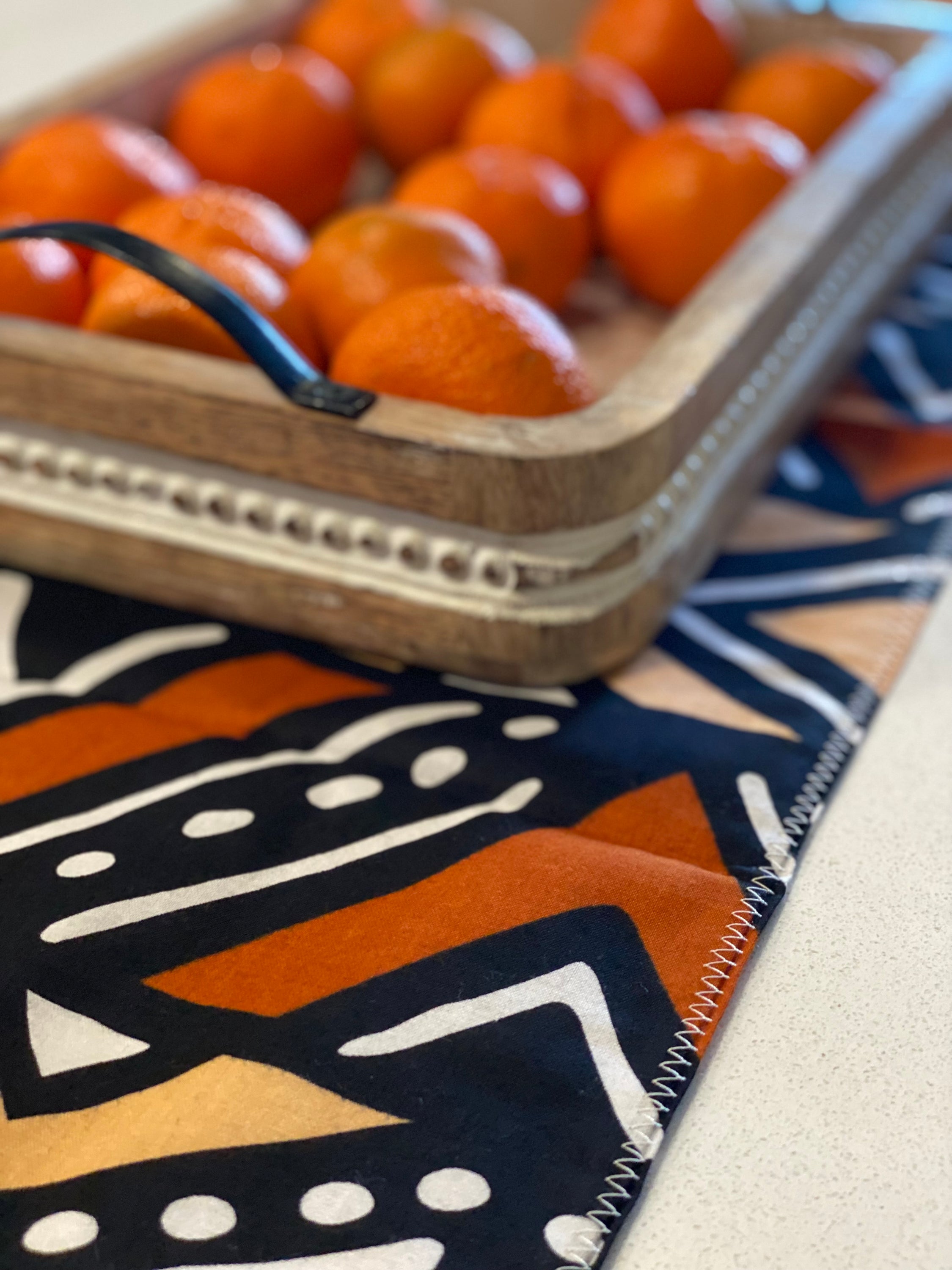 Handmade coffee table runner featuring vibrant orange Bologan wax print, showcasing intricate patterns and authentic Zimbabwean craftsmanship.