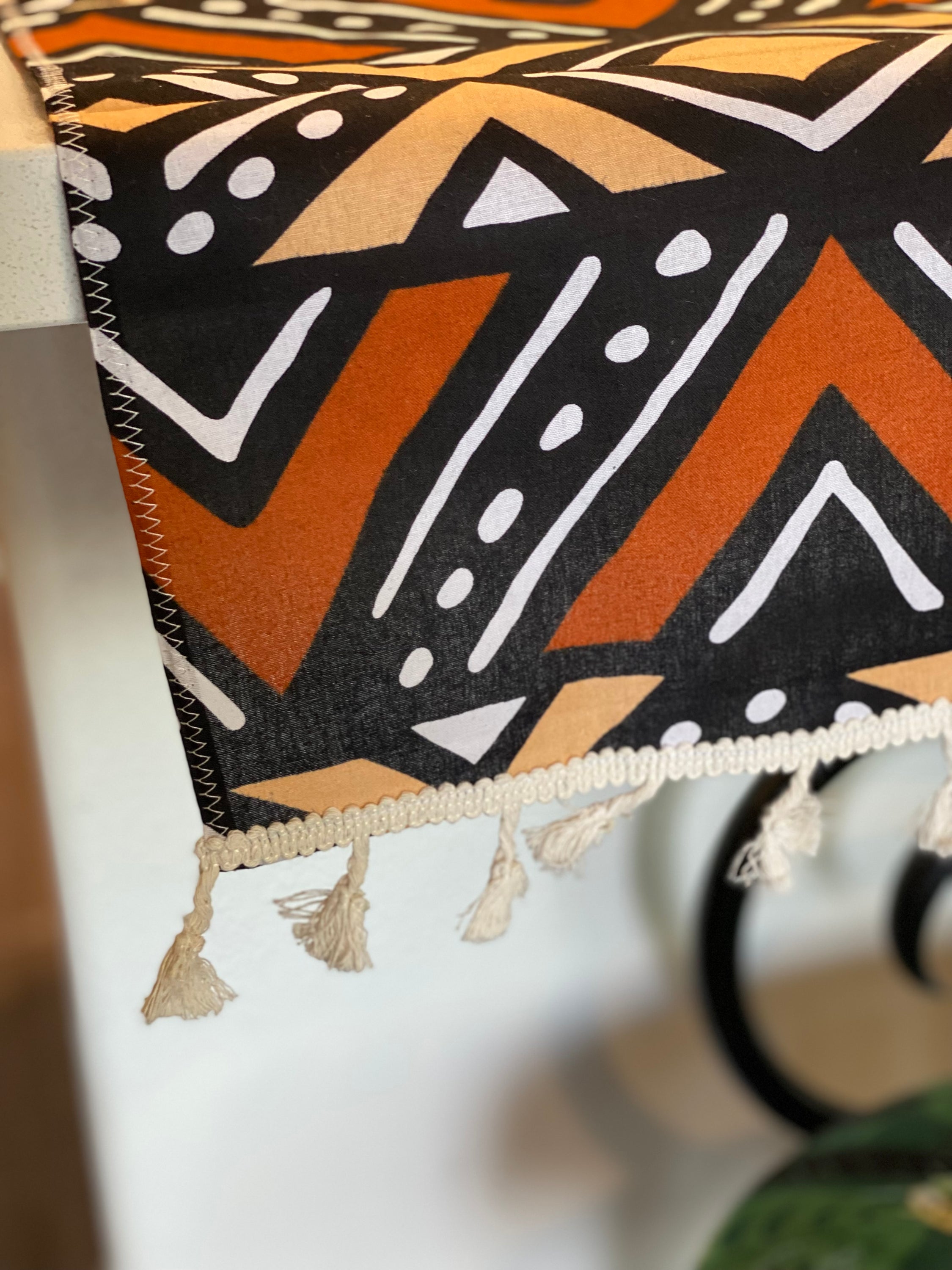 Handmade coffee table runner featuring vibrant orange Bologan wax print, showcasing intricate patterns and authentic Zimbabwean craftsmanship.