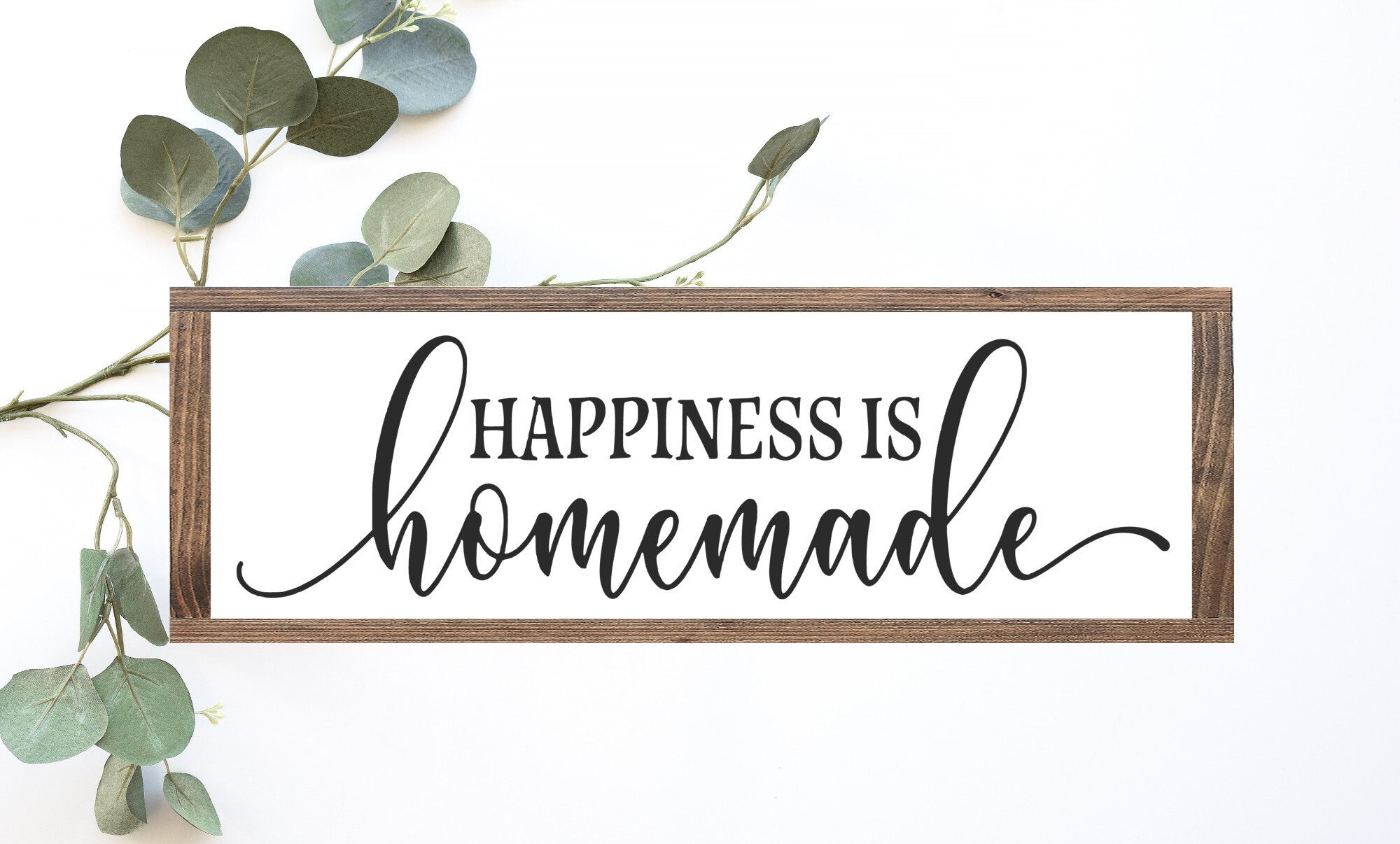 A rustic wood sign that reads 'Happiness is Homemade' in elegant lettering, featuring a matte white background and natural wood grain.