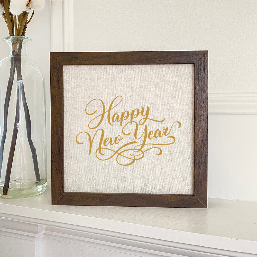 Happy New Year Gold Script Framed Sign with a stylish wood frame and linen-look background, perfect for festive decor.