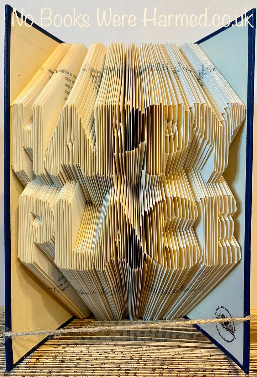 A beautifully crafted piece of book art titled HAPPY PLACE, showcasing hand-folded pages from vintage books, each unique in color and design.