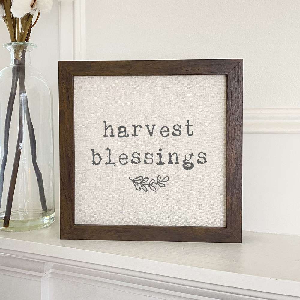 Harvest Blessings framed sign with a stylized wood frame, featuring eco-friendly inks on a linen-look background, available in walnut or white-washed.